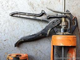 Pair of orange caulking guns. The larger gun is a heavy duty one and measures 17" over the handle.