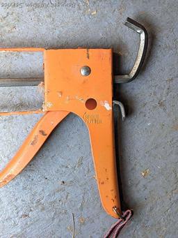 Pair of orange caulking guns. The larger gun is a heavy duty one and measures 17" over the handle.