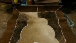 26" X 49" COWHIDE RUG, BEAR SKULL, 11 BEAR CLAWS, & A SHARK TOOTH