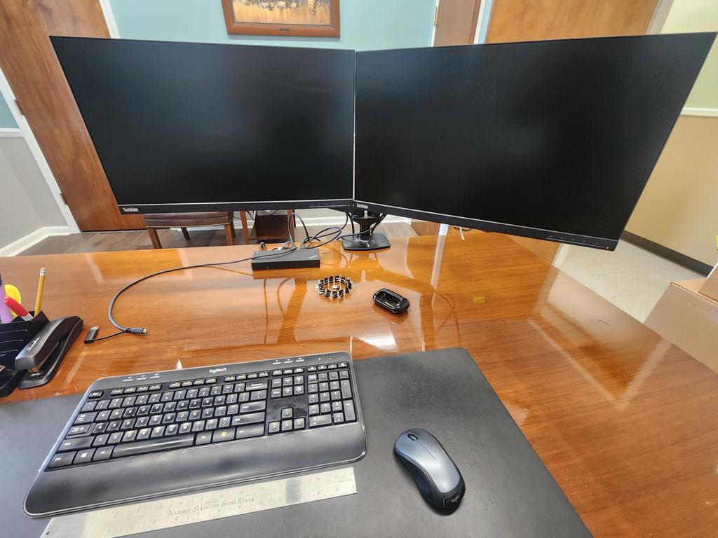 Executive office furniture with desk, chairs, and Lenovo dual monitors and keyboard
