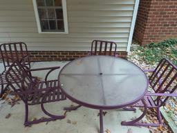 (BACK) DARK PURPLE PATIO SET WITH ROUND GLASS TOP TABLE AND 4 ARM CHAIRS. TABLE MEASURES APPROX 48"