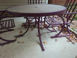 (BACK) DARK PURPLE PATIO SET WITH ROUND GLASS TOP TABLE AND 4 ARM CHAIRS. TABLE MEASURES APPROX 48"