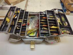 Large metal tackle box and contents including various fishing lures and other fishing accessories.