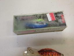 Container and contents including various fishing lures of similar style. Comes as is shown in