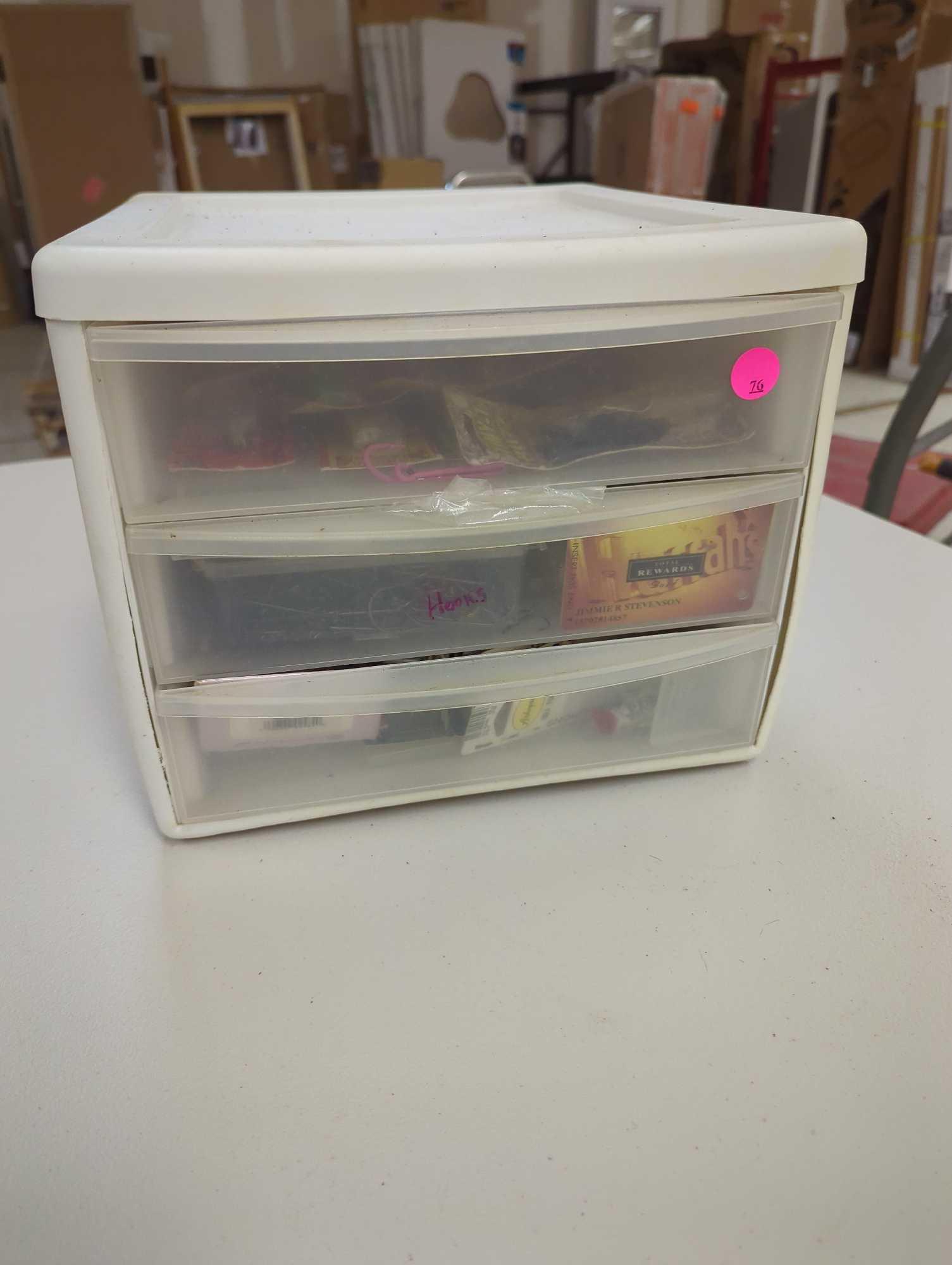 White three drawer organizer filled with unopened fishing lures and other accessories. Comes as is