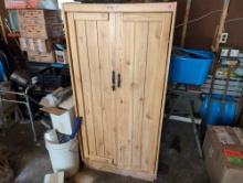(GAR) BLONDE WOOD TWO DOOR STORAGE CABINET WITH THREE INTERIOR SHELVES. DOES DISPLAY SOME WEAR. IT