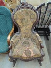 Ornately Carved Wood-Framed Rocking Chair with Worn Upholstery