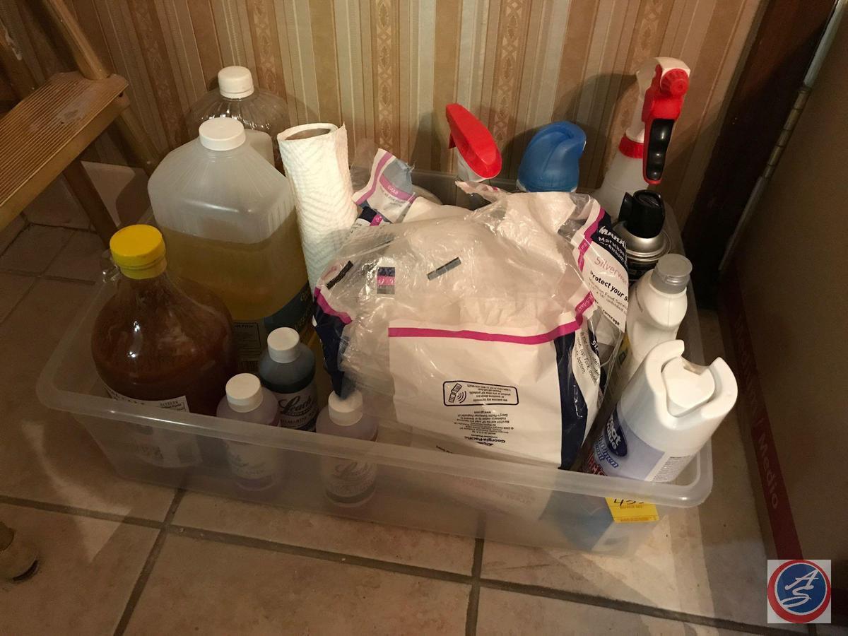 Tote containing Pine Sol, napkins, and assorted cleaning supplies