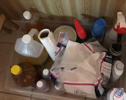 Tote containing Pine Sol, napkins, and assorted cleaning supplies