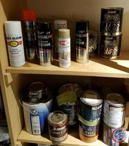 Assorted painting supplies, open cans of paint and spray paint