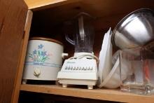CABINET LOT INCLUDING ALUM ROASTERS CAKE PANS BLENDERS CROCK POTS IRONS AND