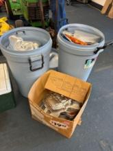 Two trash cans and a box full of cake pans