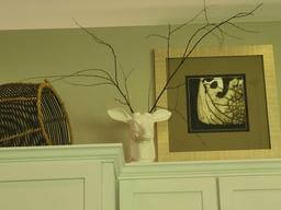Contents above refrigerator cabinets, Deer themes vase, assorted baskets, framed print and decor