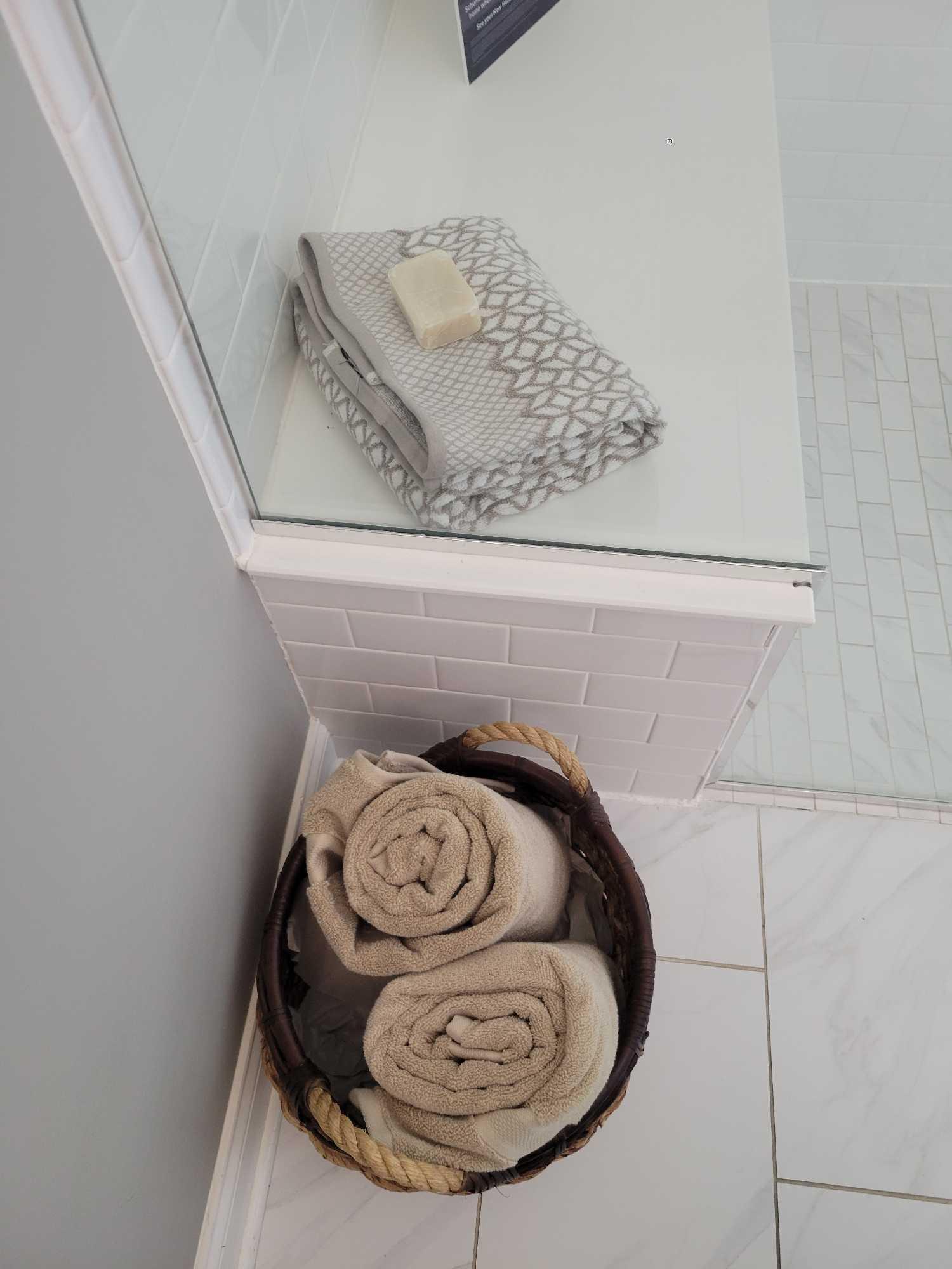 Contents of bathroon decor, rug, artificial plants, towels, basket and soap dispenser