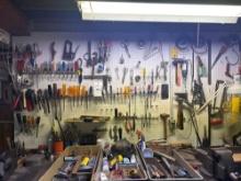 large grouping of hand, tools and hardware on workbench and pegboard