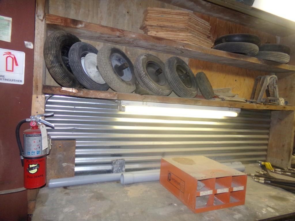 Group of Wheelbarrow Parts, Tires, Rims and Hand Sprayer Parts on Wall Over