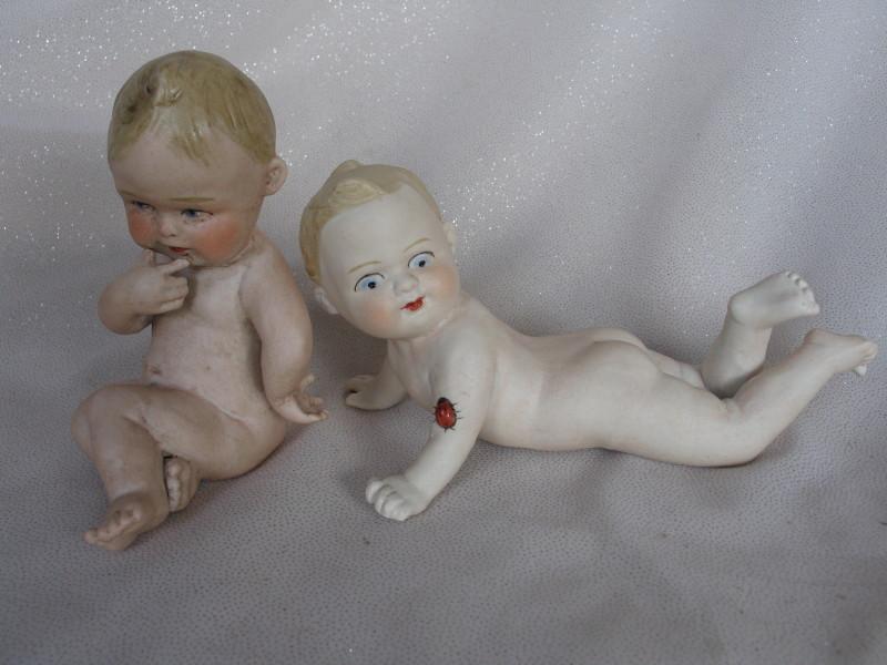 Two bisque Piano Babies:- Seated 13cm brown molded hair, painted features,