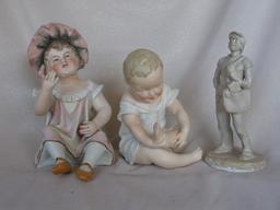 Three Figurines:- Bisque Heubach type 15cm seated boy with crossed legs inc