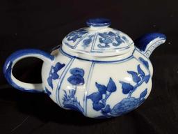 A blue and white porcelain teapot painted with flowers and lilly pads