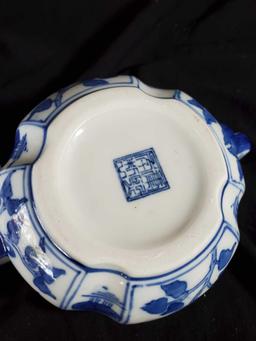 A blue and white porcelain teapot painted with flowers and lilly pads