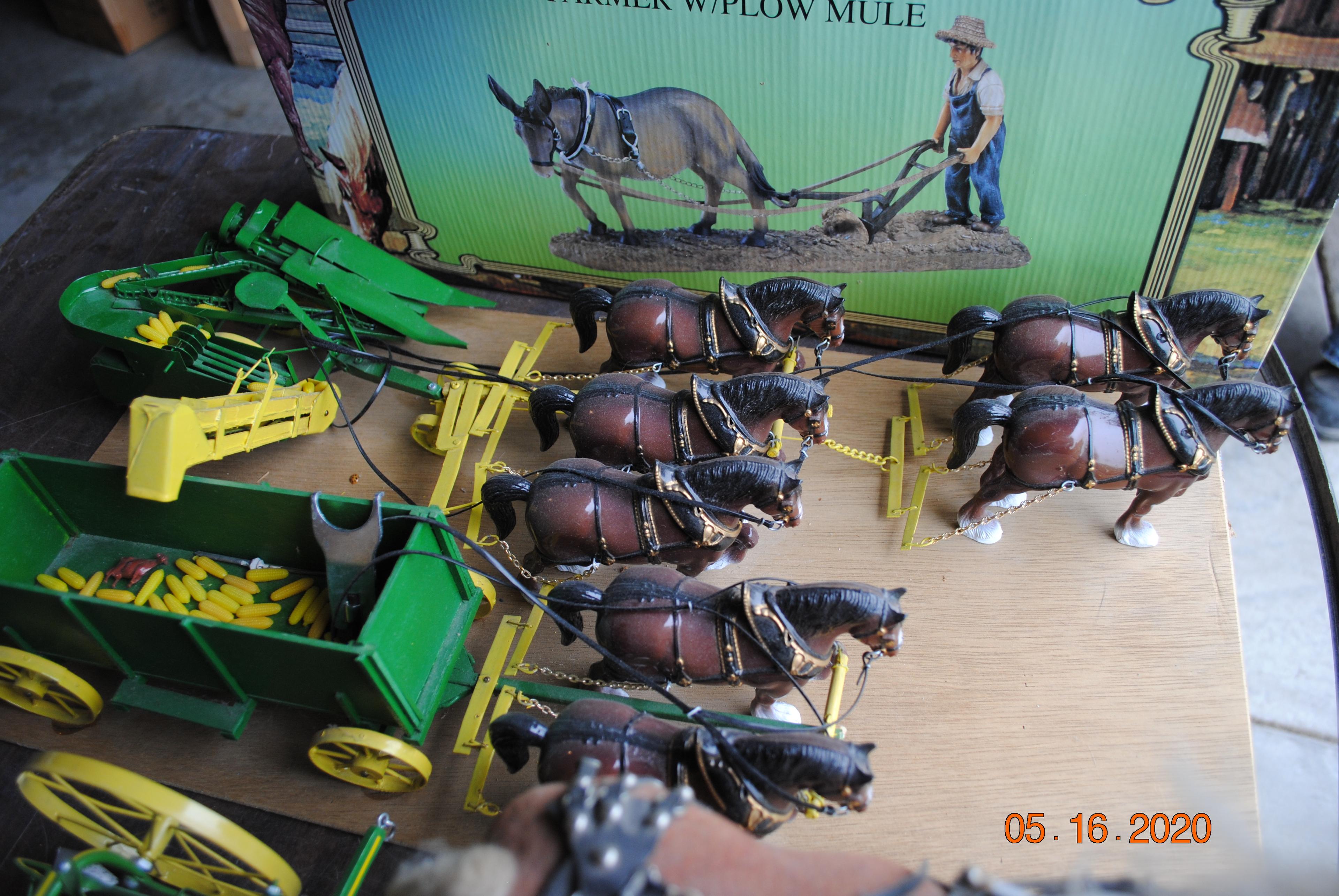 Horses pulling farm equipment including green cultivator, green corn picker & green barge box, red c