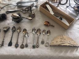 Silver spoons in holder, tea strainer, utensils, salt and peppers, candleholders, polish rag and