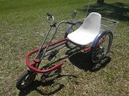 Side-entry, sit-down tricycle with white plastic seat and metal basket.