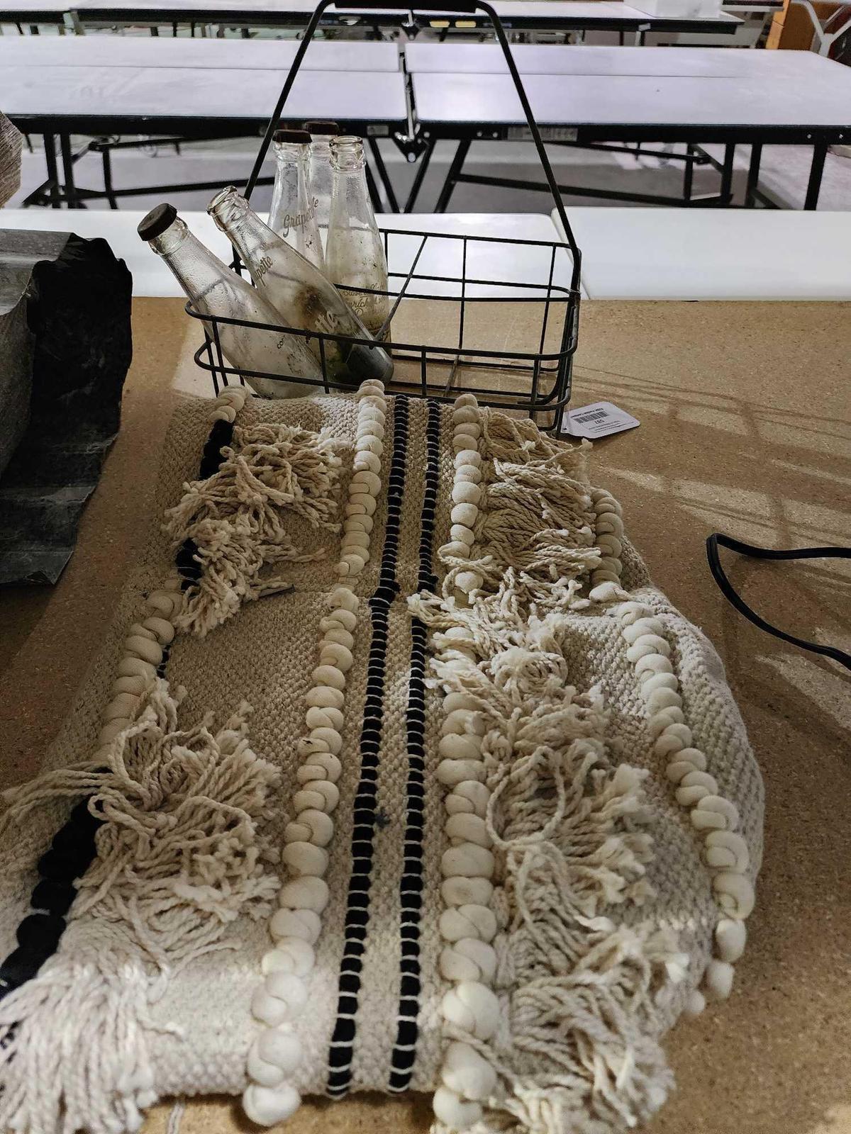 Fringed carpet bag and one old metal milk delivery tray and five 6 oz glass Grapette soda bottles.