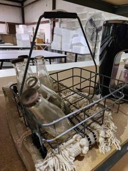 Fringed carpet bag and one old metal milk delivery tray and five 6 oz glass Grapette soda bottles.