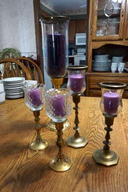Five brass candle sticks with purple candles.