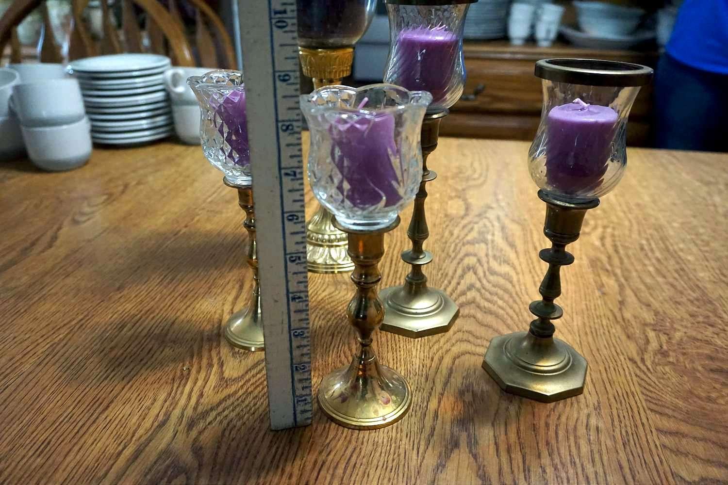 Five brass candle sticks with purple candles.