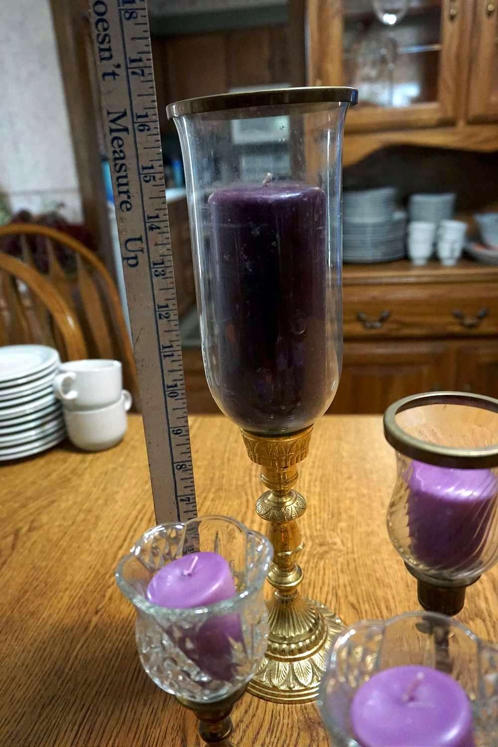 Five brass candle sticks with purple candles.