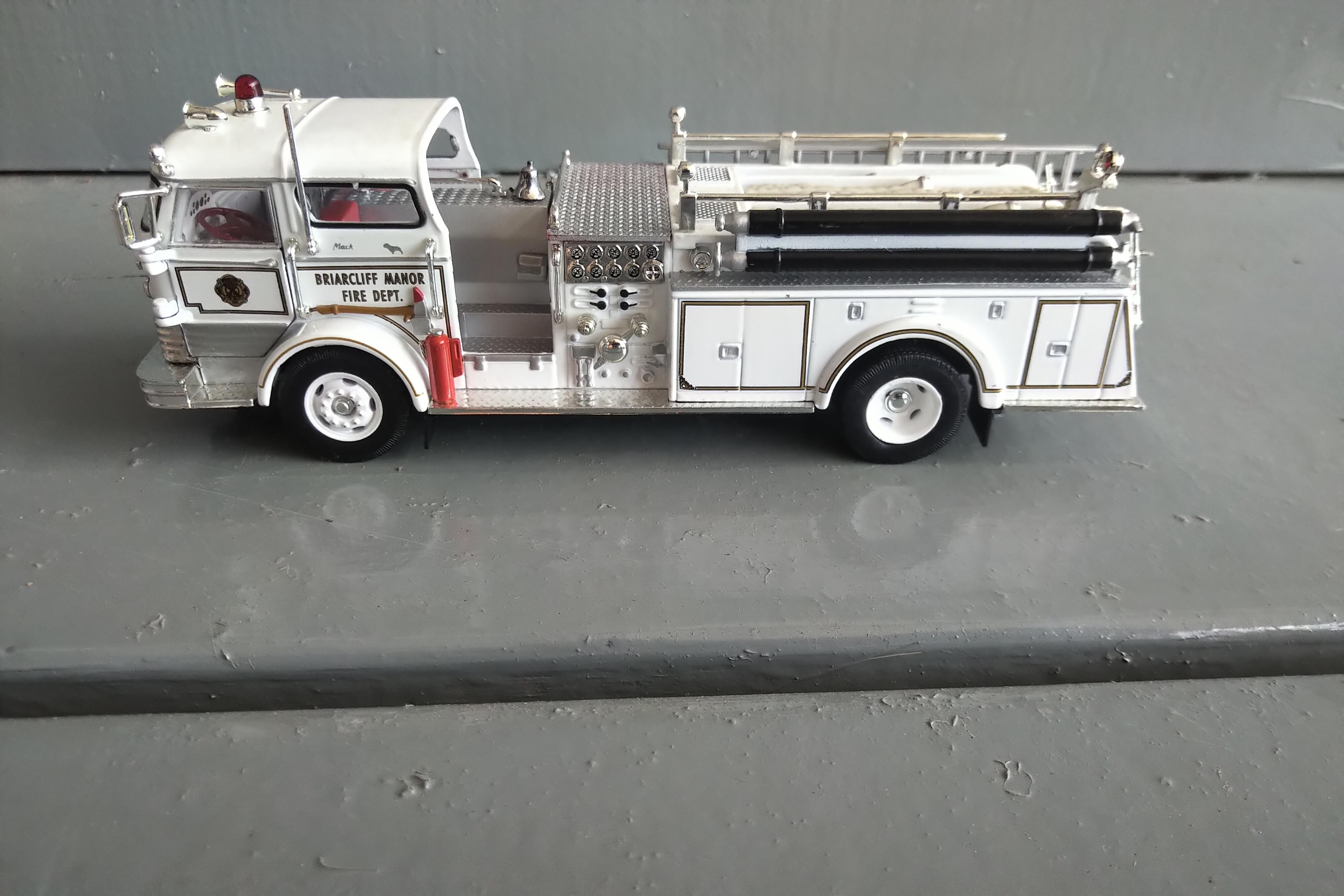 A TUBE OF 12 - 1/64 SCALE FIRE TRUCKS, A 1/64 SCALE POLICE CAR