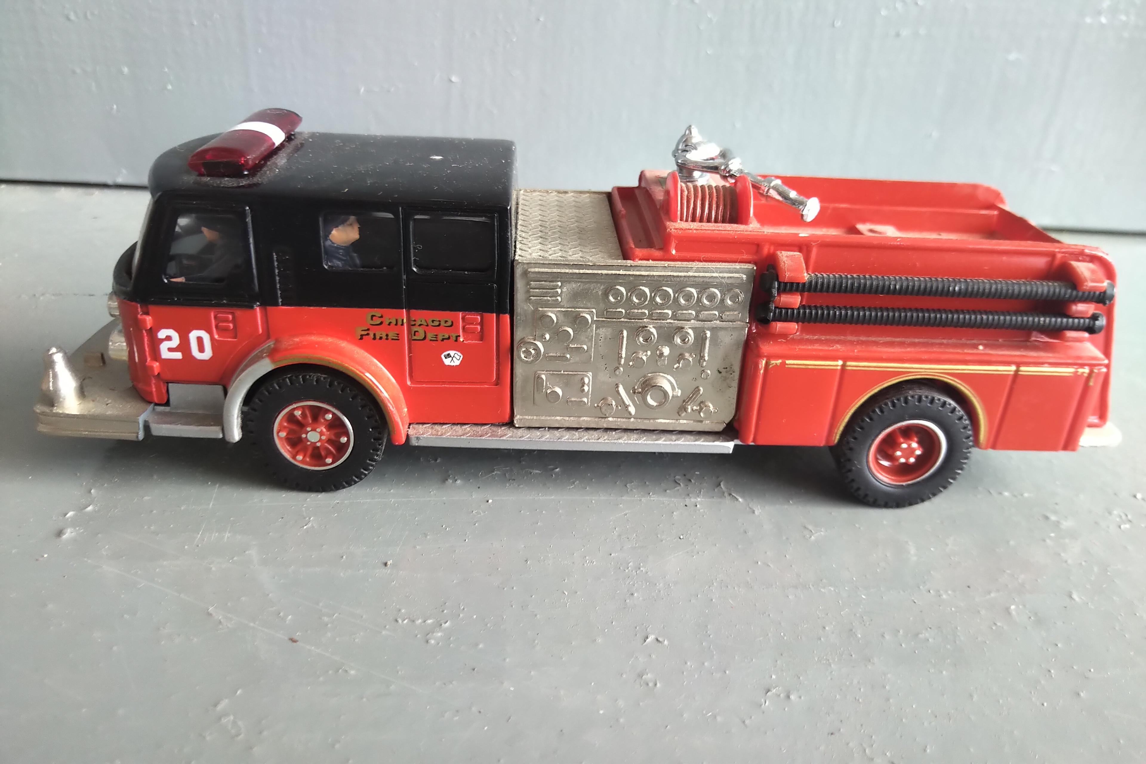 A TUBE OF 12 - 1/64 SCALE FIRE TRUCKS, A 1/64 SCALE POLICE CAR