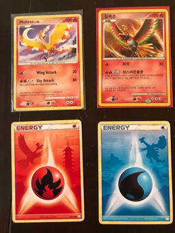 4 Pokemon Cards Moltres Level 42 Card Ho-Oh 2 Energy Cards with Pokemon Shadows in the Background