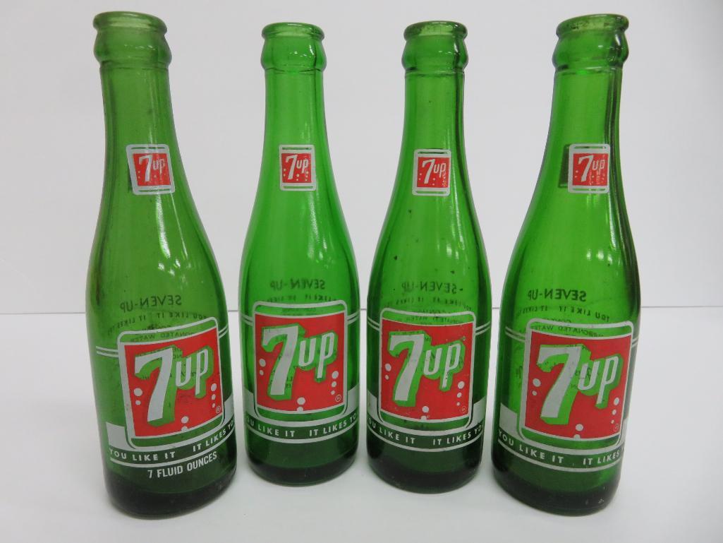 Seven assorted types and sizes of vintage 7 up bottles and paper carrier