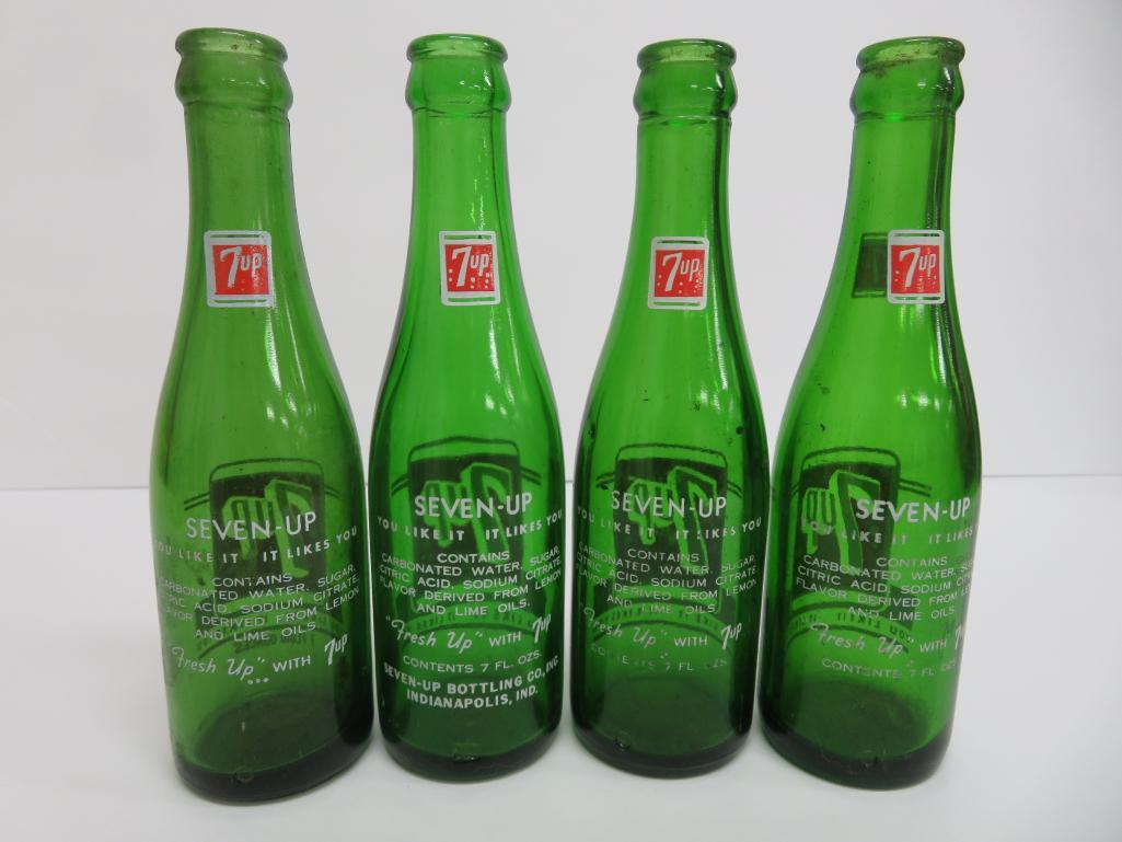 Seven assorted types and sizes of vintage 7 up bottles and paper carrier