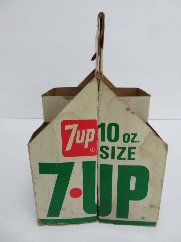 Seven assorted types and sizes of vintage 7 up bottles and paper carrier