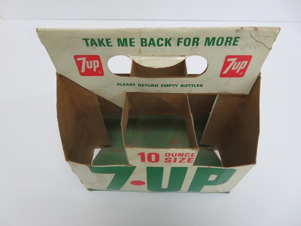 Seven assorted types and sizes of vintage 7 up bottles and paper carrier