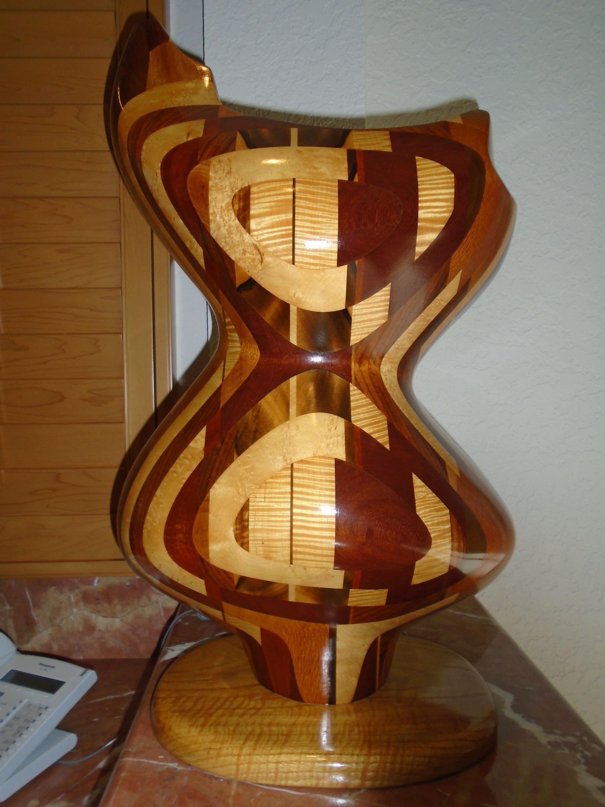 Large curvy shaped wood sculpture on a wood base.