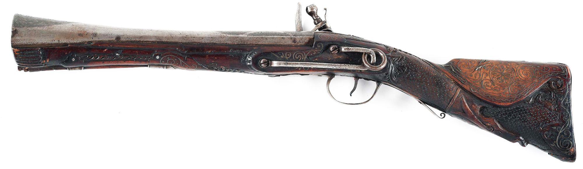 (A) HIGHLY DECORATED OTTOMAN FLINTLOCK KNEE GUN, WITH EXTENSIVE CARVING AND SILVER WIRE INLAY.