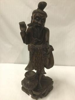 Carved wooden state of an Asian man carrying a jar and a net or pelts