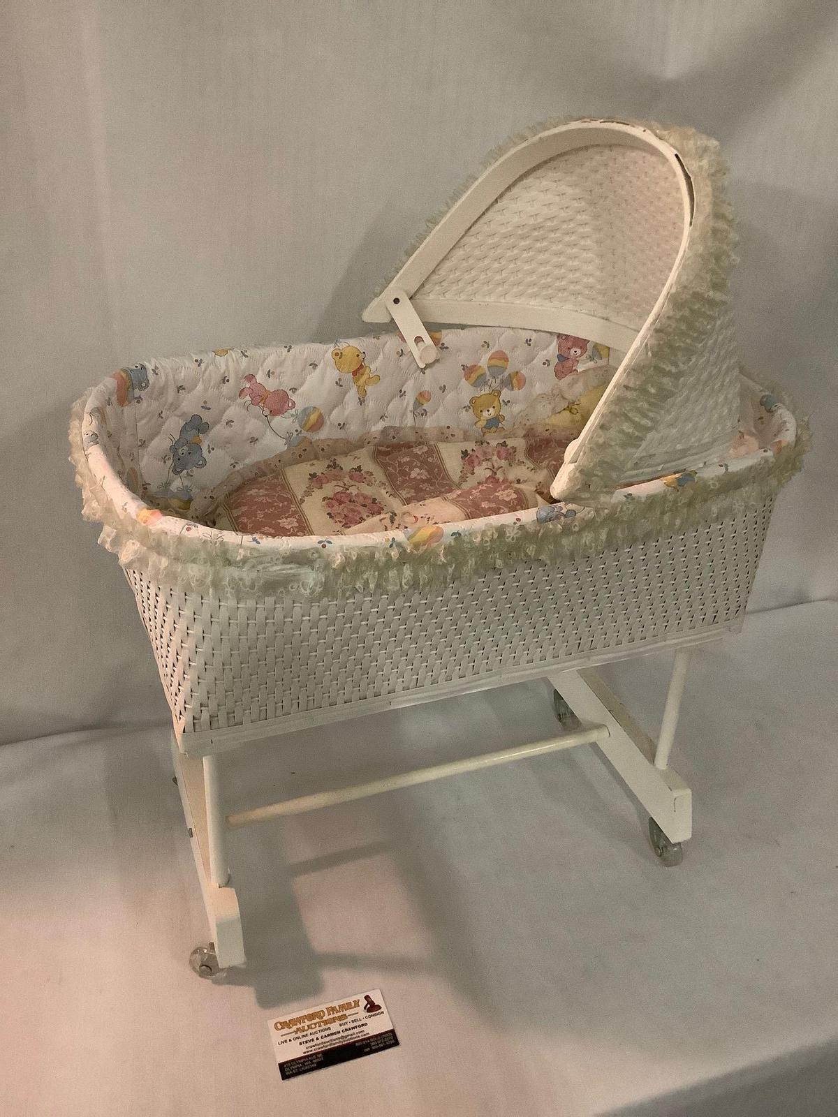 Vintage white painted wood and wicker baby doll bassinet on wheels, approx 18x14x24 inches.