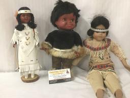 Three porcelain, wood, and vinyl dolls with indigenous garb, from makers like Regal. Largest doll