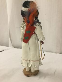 Three porcelain, wood, and vinyl dolls with indigenous garb, from makers like Regal. Largest doll