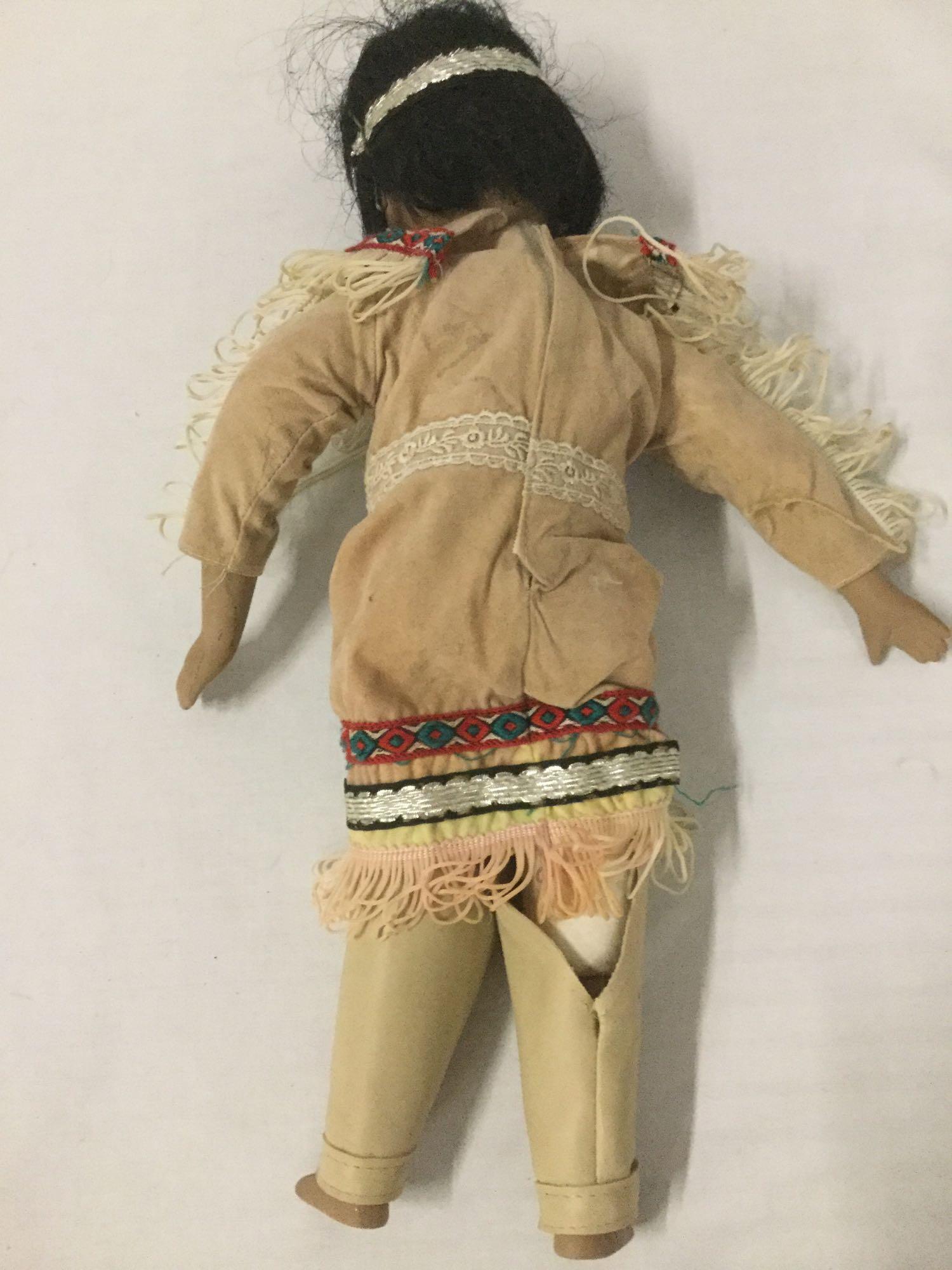 Three porcelain, wood, and vinyl dolls with indigenous garb, from makers like Regal. Largest doll