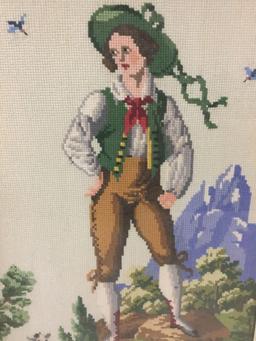 2 framed needlepoint art pieces of boy and girl in mountain scenes.