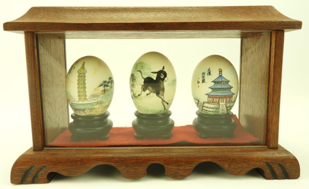 Lot 1711 - (3) Oriental painted eggs in small showcase