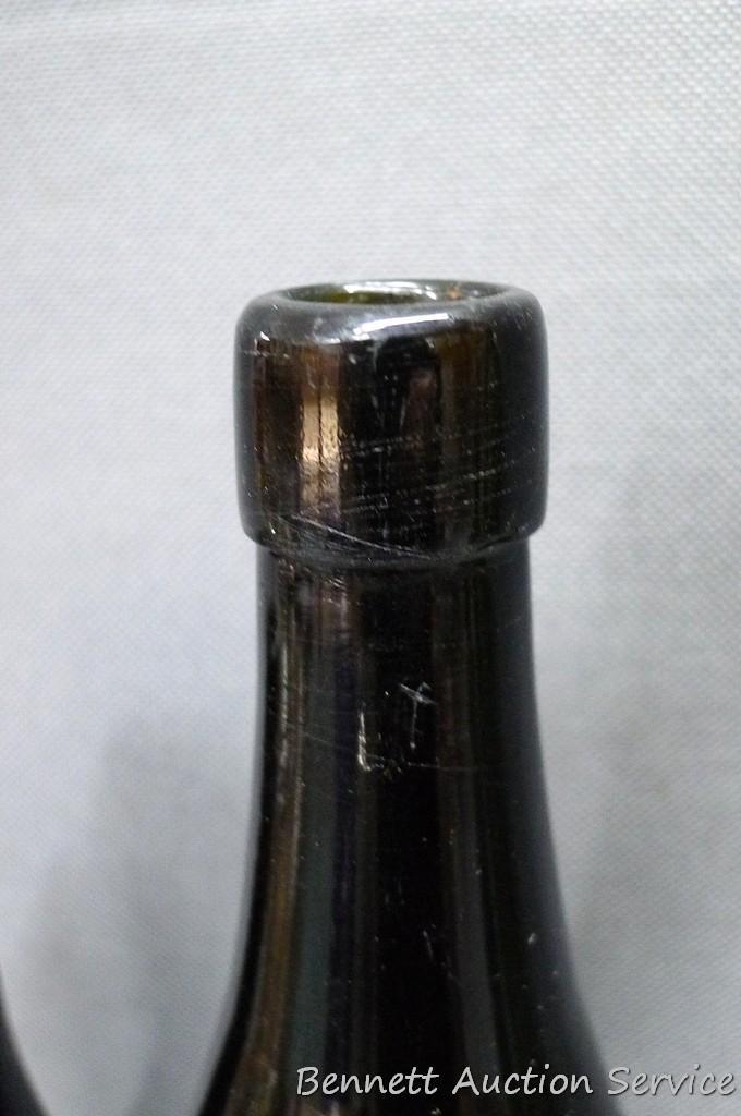 Tall green glass bottle with an interesting design stamped seal at base of bottle neck, measures 3"