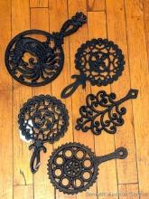 Five cast iron trivets, largest is approx 11" long